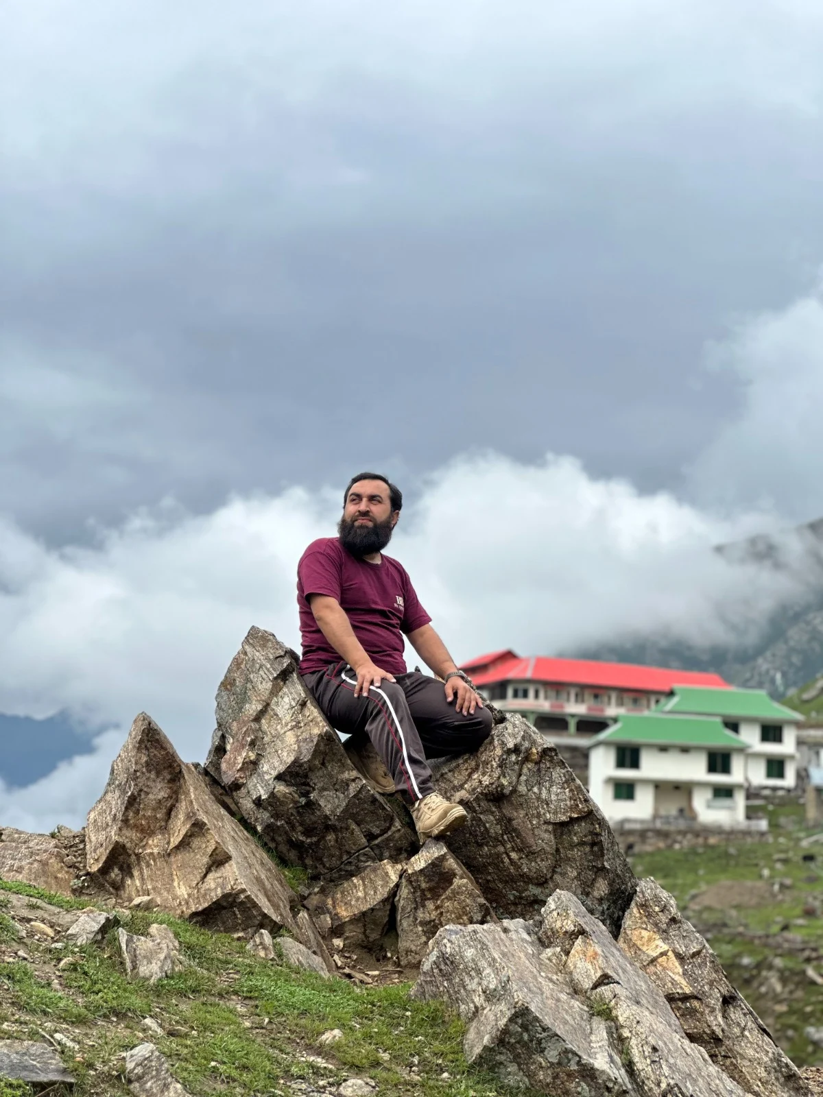 Abdullah sitting on rugged rocks beneath drifting clouds